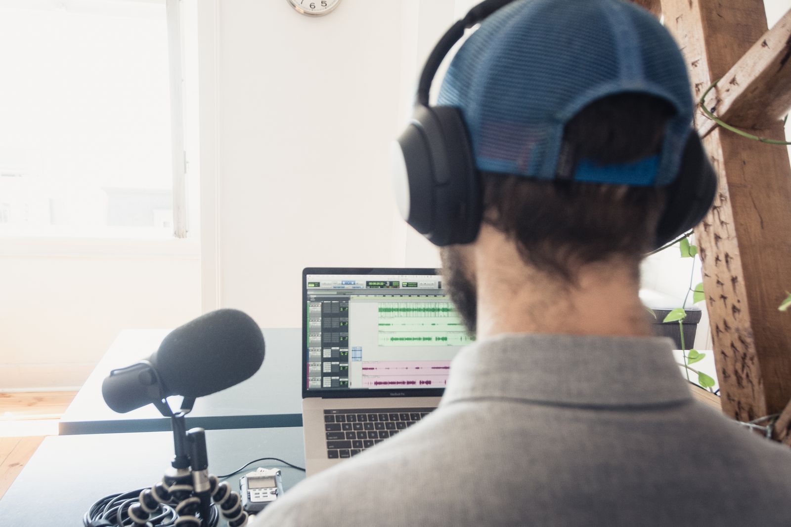 A podcast producer editing an episode on a laptop with audio waveforms visible on screen