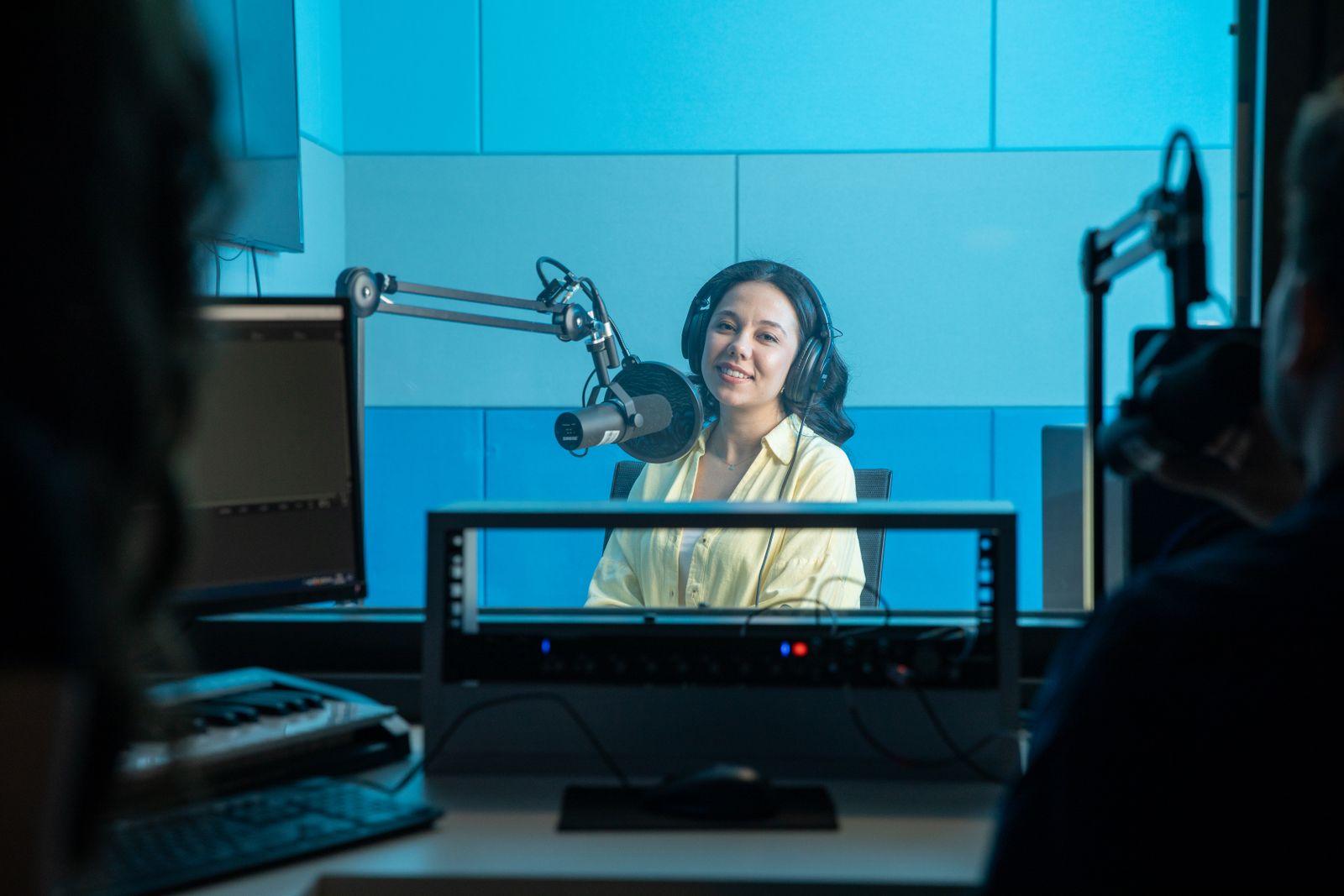 A podcast guest wearing a headset and speaking into a microphone in a studio